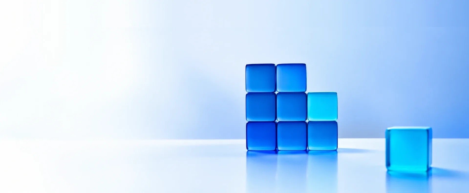 Cubes de verre bleus alignés sur une surface claire, illustrant les offres MADCRM qui s'assemblent selon votre croissance